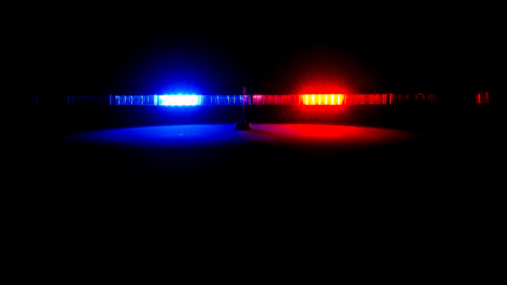 Sirene de luzes azul e vermelha em destaque contra um fundo escuro, simbolizando ação policial e a importância de um falso pai de santo.