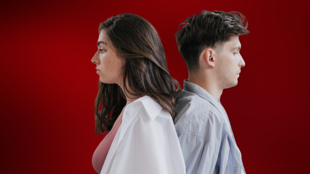 Homem e mulher de costas um para o outro, ambos com expressões sérias, simbolizando distanciamento emocional ou conflito em um relacionamento. Eles estão em um fundo vermelho intenso, sugerindo uma atmosfera tensa ou emocionalmente carregada.