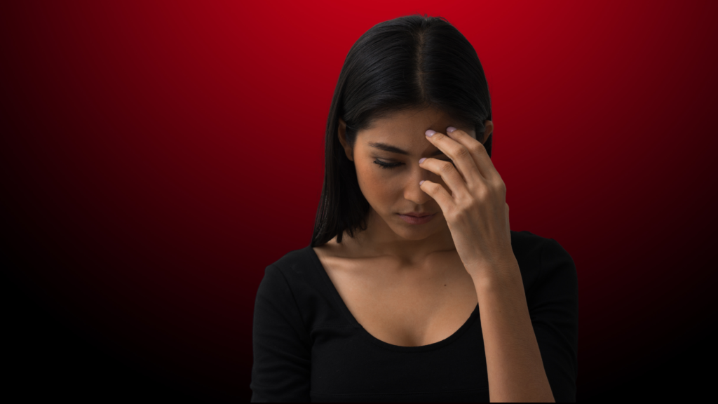 Uma mulher com expressão pensativa e preocupada, com a mão na testa, transmitindo angústia ou confusão emocional. O fundo em tons de vermelho escuro cria uma atmosfera intensa, sugerindo sentimentos internos profundos e conflituosos.