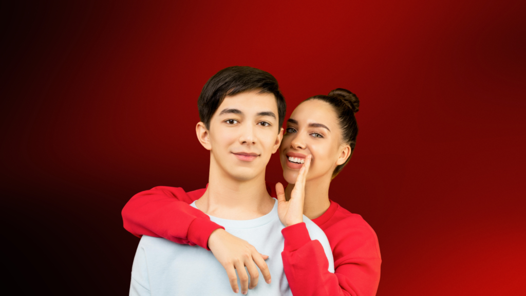 Casal sorridente em clima descontraído, com a mulher sussurrando algo divertido ao ouvido do homem, simbolizando leveza, conexão e autoconfiança na paquera.