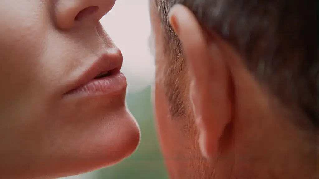 Mulher sussurrando no ouvido de um homem em momento íntimo, ilustrando o que dizer para apimentar a relação com palavras provocantes e cheias de desejo.