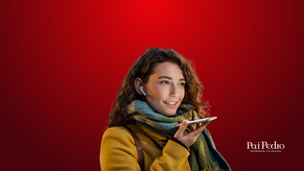 Mulher sorridente falando com o celular no modo viva-voz, usando fones de ouvido. Ela veste casaco amarelo e cachecol, em um fundo vermelho intenso. A imagem simboliza o ato de mandar uma mensagem ou áudio com palavras sinceras para se desculpar com o namorado. Representa reconciliação amorosa por meio da comunicação virtual. No canto inferior direito está o logo de Pai Pedro — Quimbanda Luciferiana.