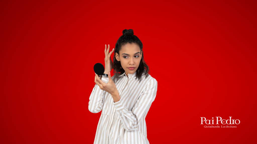 Mulher jovem de aparência séria olha para o espelho de maquiagem que segura com uma das mãos enquanto arruma o cabelo com a outra, simbolizando como ser menos insegura. Ela veste uma camisa listrada e está em um fundo vermelho vibrante. O logotipo "Pai Pedro - Quimbanda Luciferiana" aparece no canto inferior direito. 