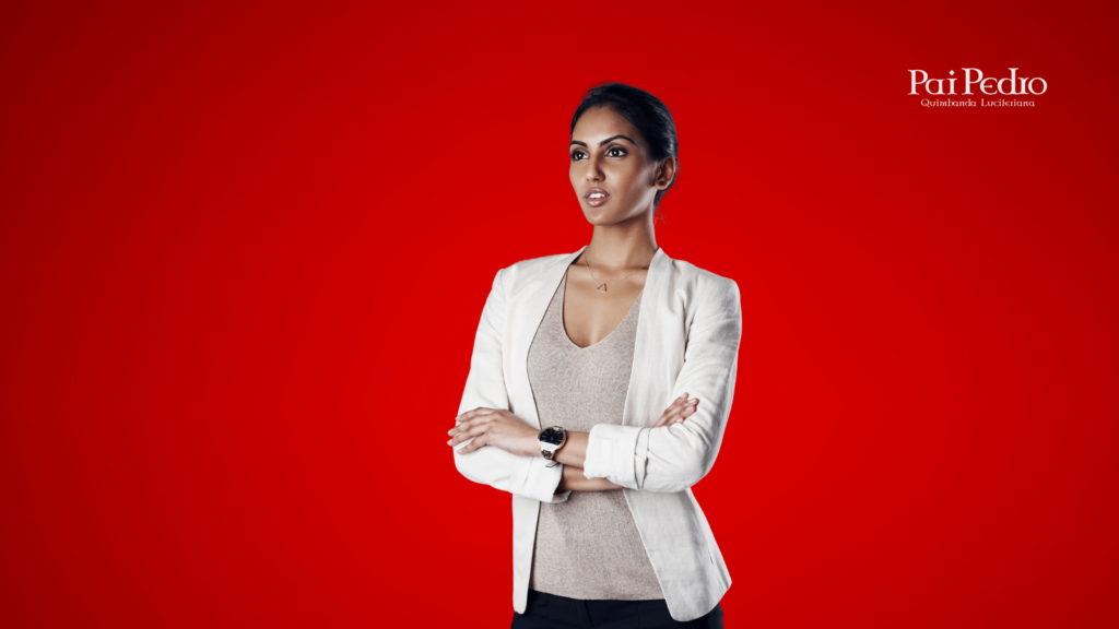 Mulher confiante com os braços cruzados e olhar determinado, simbolizando a atitude de manter a calma e o autocontrole após ouvir que o parceiro pediu um tempo. Ela veste blazer claro e está sobre um fundo vermelho.