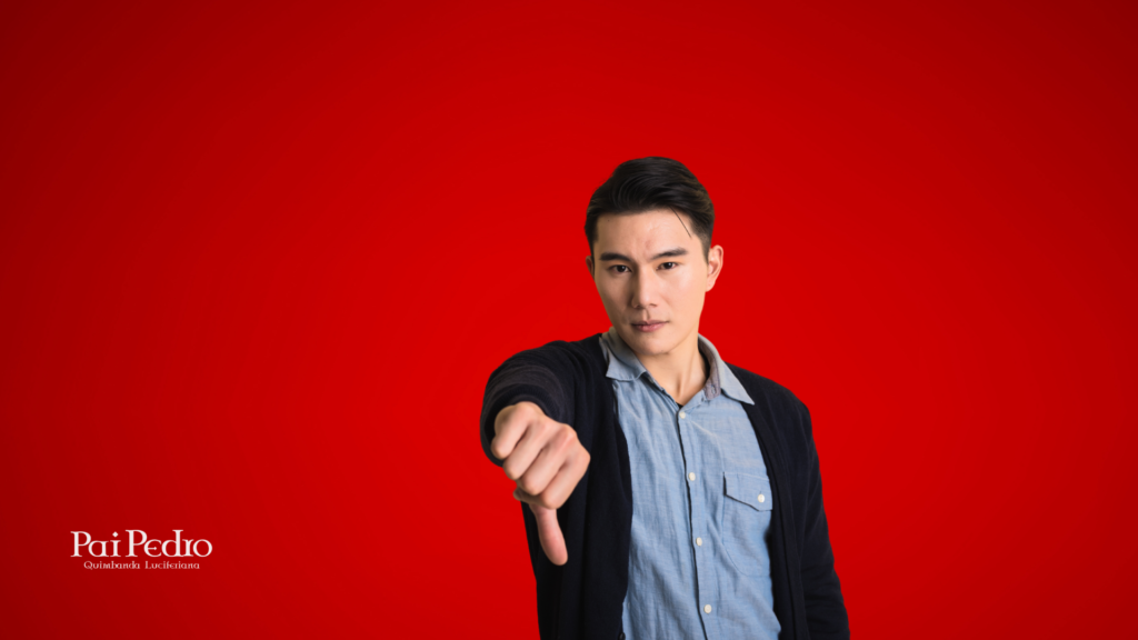 Homem com expressão séria e olhar direto, fazendo sinal de “negativo” com o polegar para baixo, sobre fundo vermelho intenso. Representa o claro desinteresse ou rejeição — um dos sinais de que ele realmente não te quer.