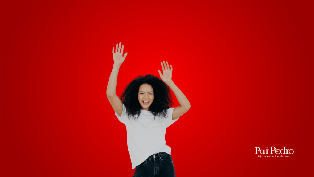 Mulher jovem de braços erguidos e sorriso aberto em frente a um fundo vermelho vibrante, simbolizando autoconfiança, liberdade e superação emocional para lidar com a paixão platônica.