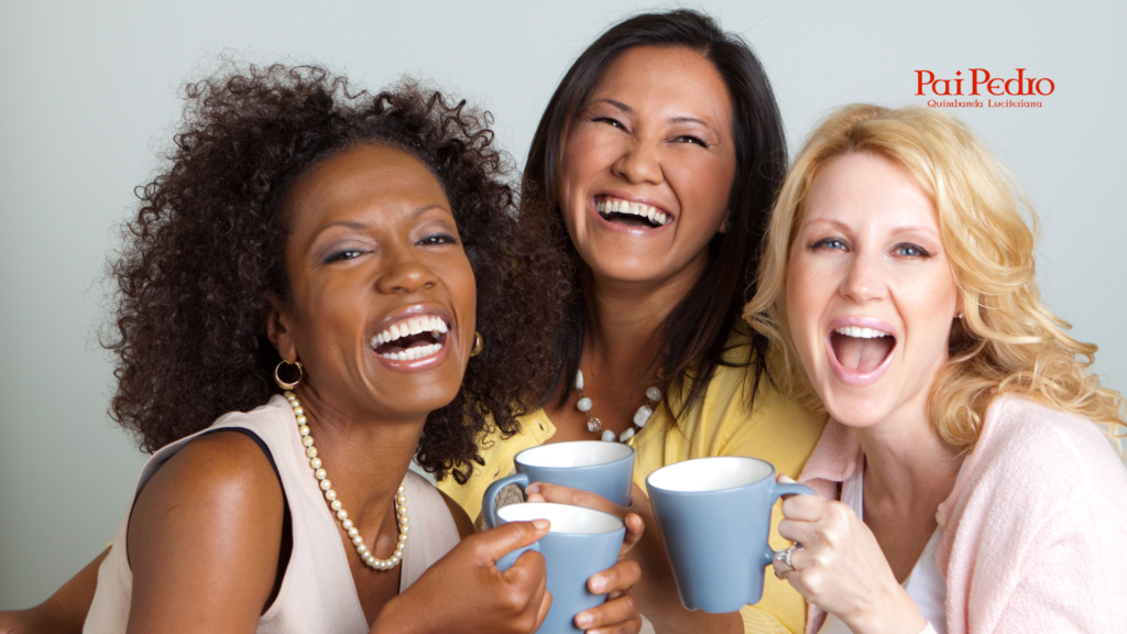 Três mulheres sorridentes segurando xícaras de café, compartilhando um momento de alegria e conexão, simbolizando abertura para novas relações e experiências sociais.