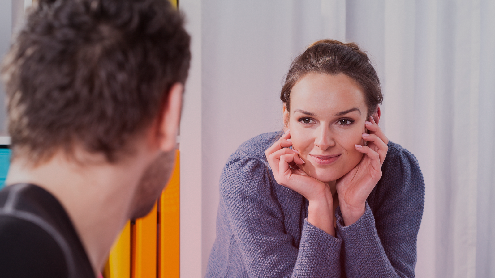 Uma mulher com expressão carinhosa e pensativa, apoiando o rosto nas mãos enquanto olha para um homem. Ela parece interessada e envolvida na conversa, sugerindo uma conexão emocional ou amizade próxima, um relacionamento platônico