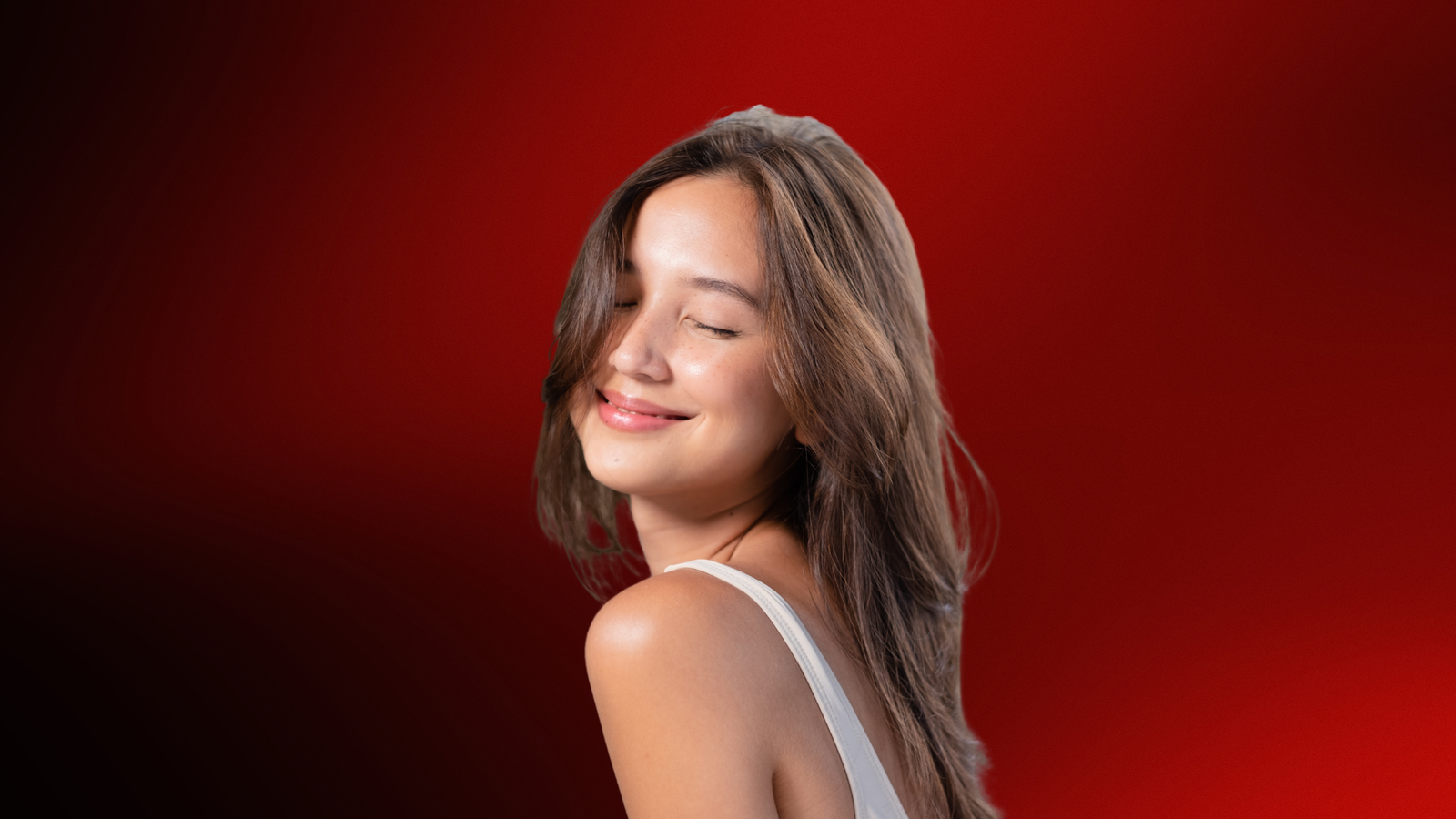 Mulher sorridente de olhos fechados com expressão confiante e serena, sobre um fundo vermelho vibrante, representando o charme e a leveza do flerte feminino.