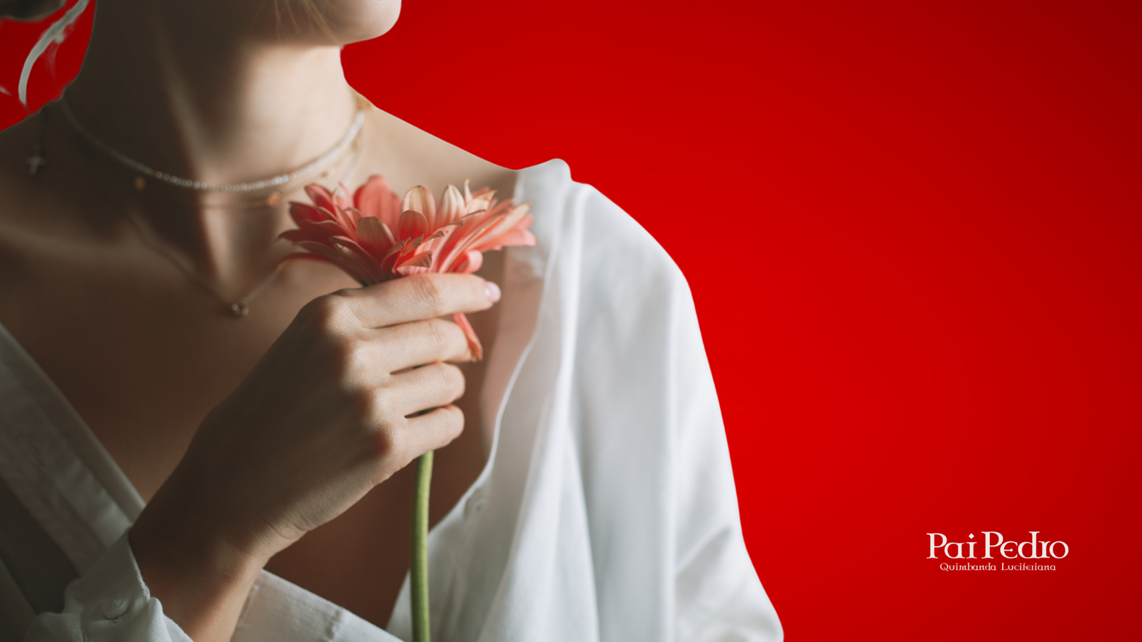 Mulher segurando uma flor cor-de-rosa próxima ao peito, com expressão suave e fundo vermelho vibrante. Ela veste camisa branca aberta, transmitindo delicadeza, autocuidado e conexão com a energia feminina.